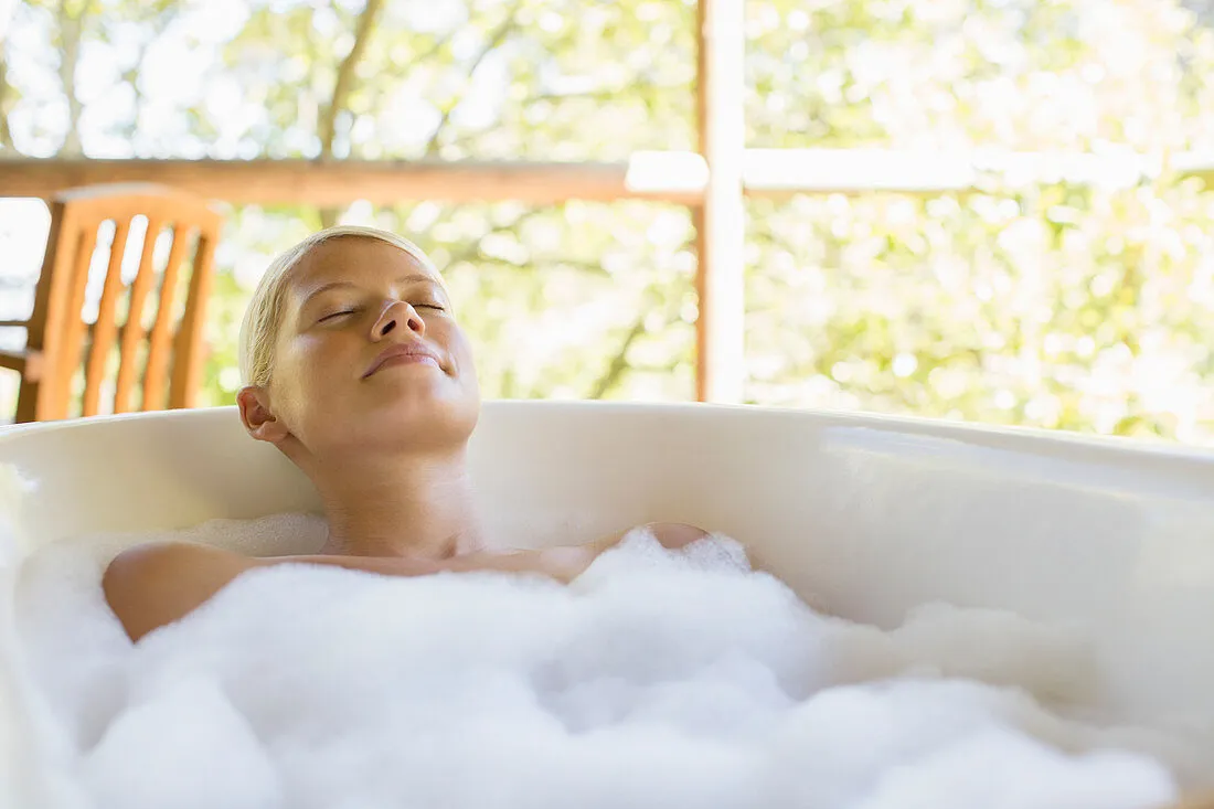 Woman relaxing in bathtub.
