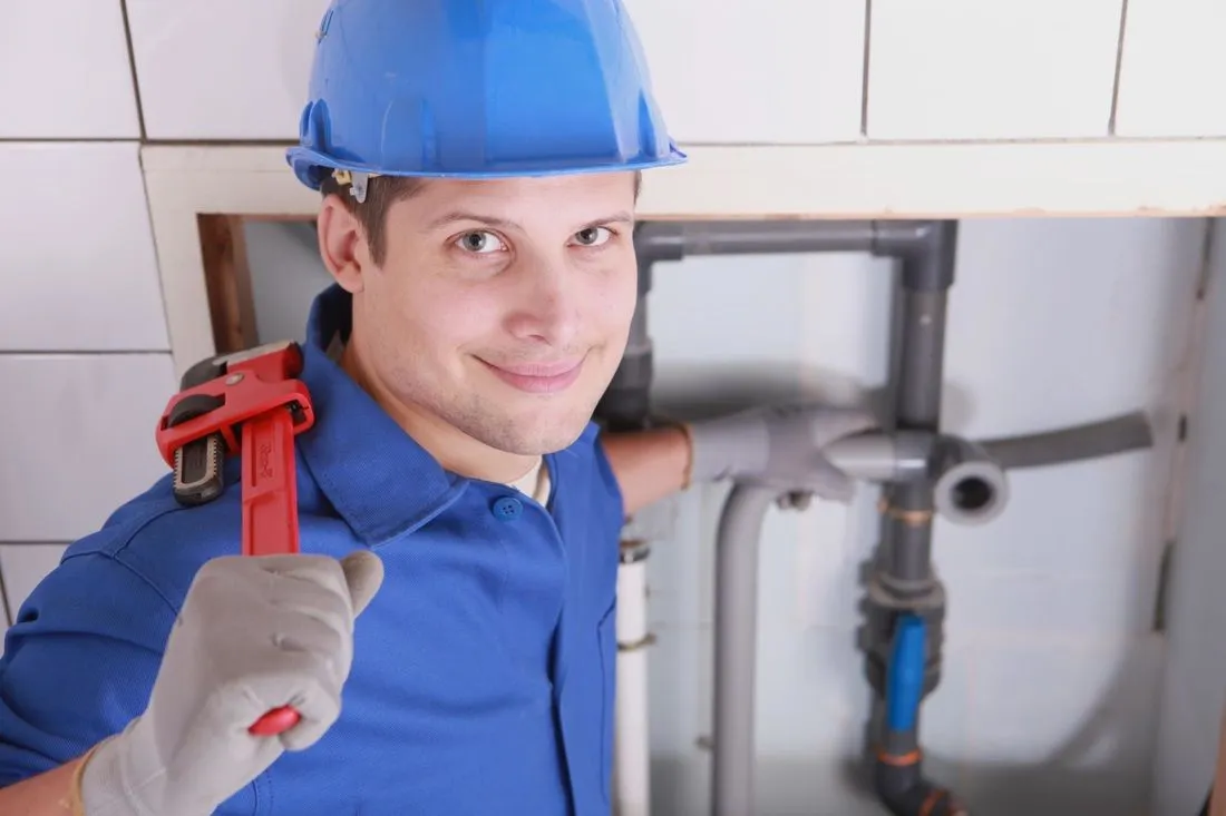 A man in blue shirt and hat holding a wrench