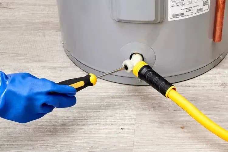 A person in a blue gloves is using a tool to a fix a water heater