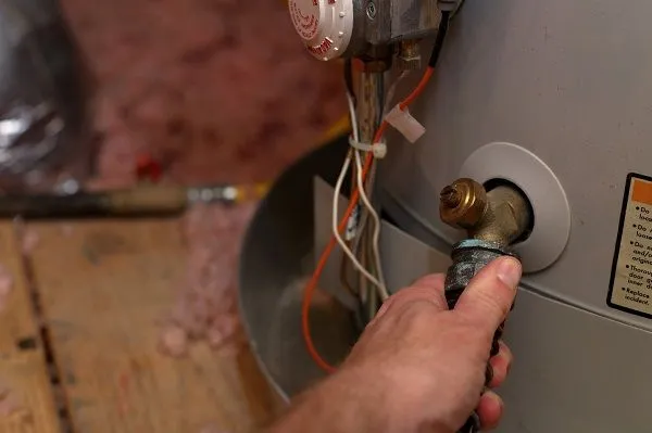 Close-up of a person performing maintenance on a water heater