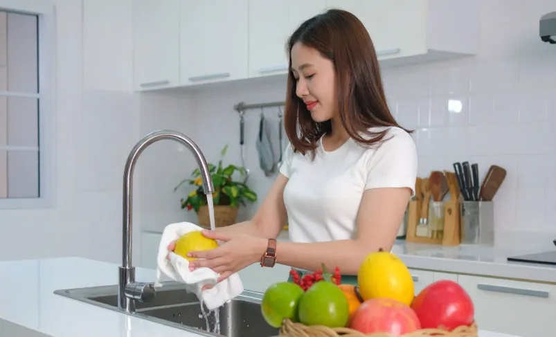 Woman washing fruit with hot water