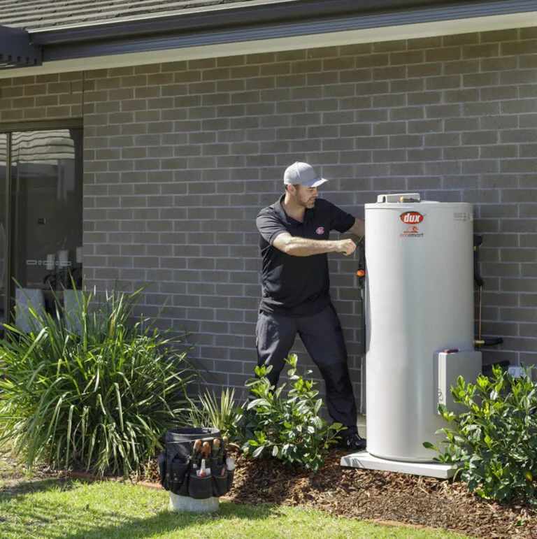 Dux heat pump hot water system installed against a modern brick residential wall
